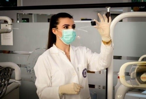 female scientist wearing mask looking at a small black rectangular item