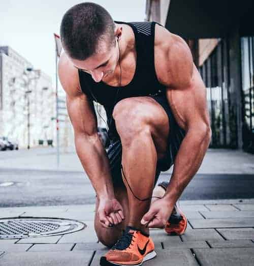 male jogger bending over to tie shoelaces