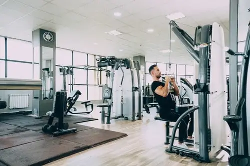 man using lat pull down machine in an empty gym