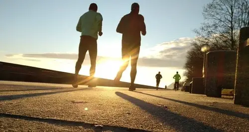 two men running together at sunset