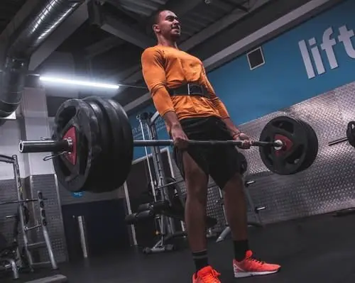 man performing deadlifts in a gym