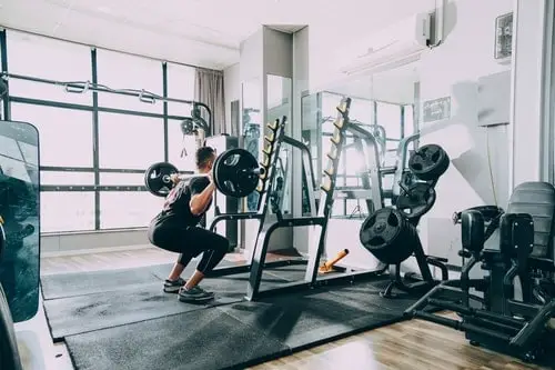 man doing squats with barbell in personal training studio 