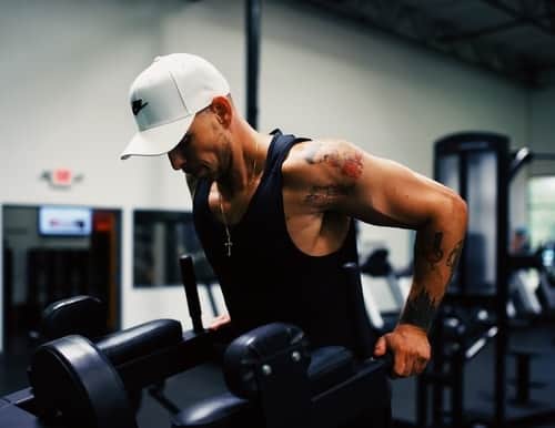 man wearing baseball hat doing dips in a gym