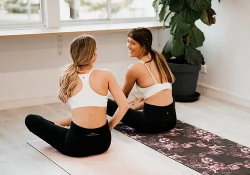 two women talking on yoga mats