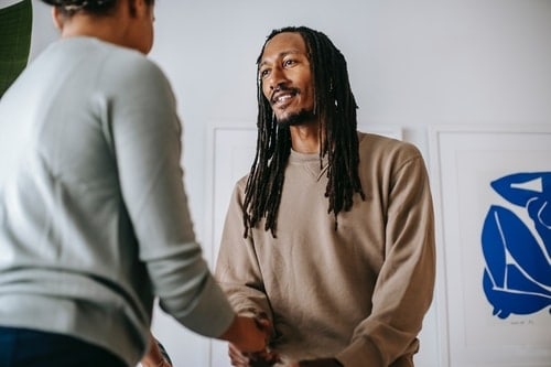 Young man with dreadlocks shaking womans hand