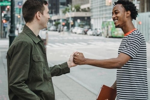 two young men fist bumping each other and smiling