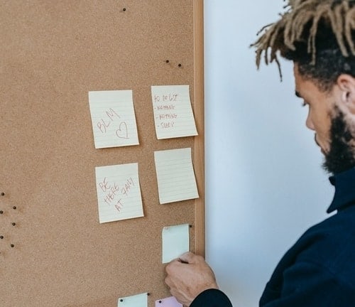 man using post it notes on pin board